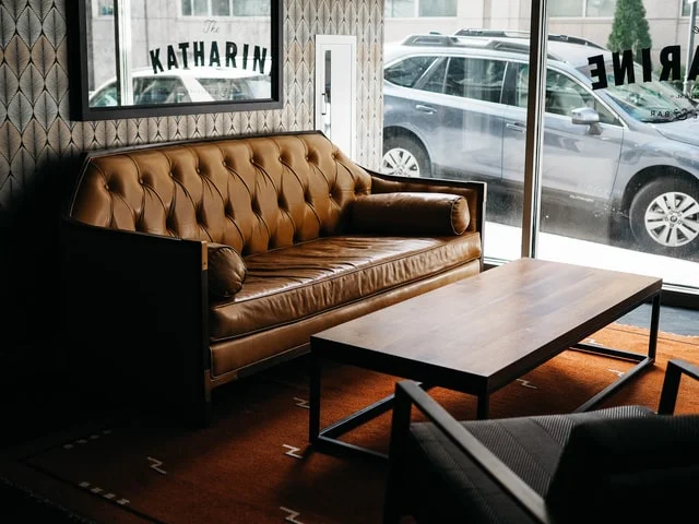 Modern living room with a brown leather sofa next to a window, illustrating How to clean the leather sofa