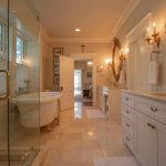 Spacious and elegant bathroom featuring a glass shower, freestanding bathtub, and vanity with dual sinks, offering a great example of bathroom remodeling ideas. The room is bright and well-lit, with classic fixtures and a clean, modern aesthetic