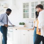 A professional showing potential buyers a sparkling, well-maintained kitchen, highlighting the importance of pre sale cleaning and staging before listing a home.