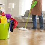 Clean your house in 30 minutes demonstrated with a cleaning bucket filled with supplies, while a person mops the floor in a living room, showing a quick and efficient cleaning process.